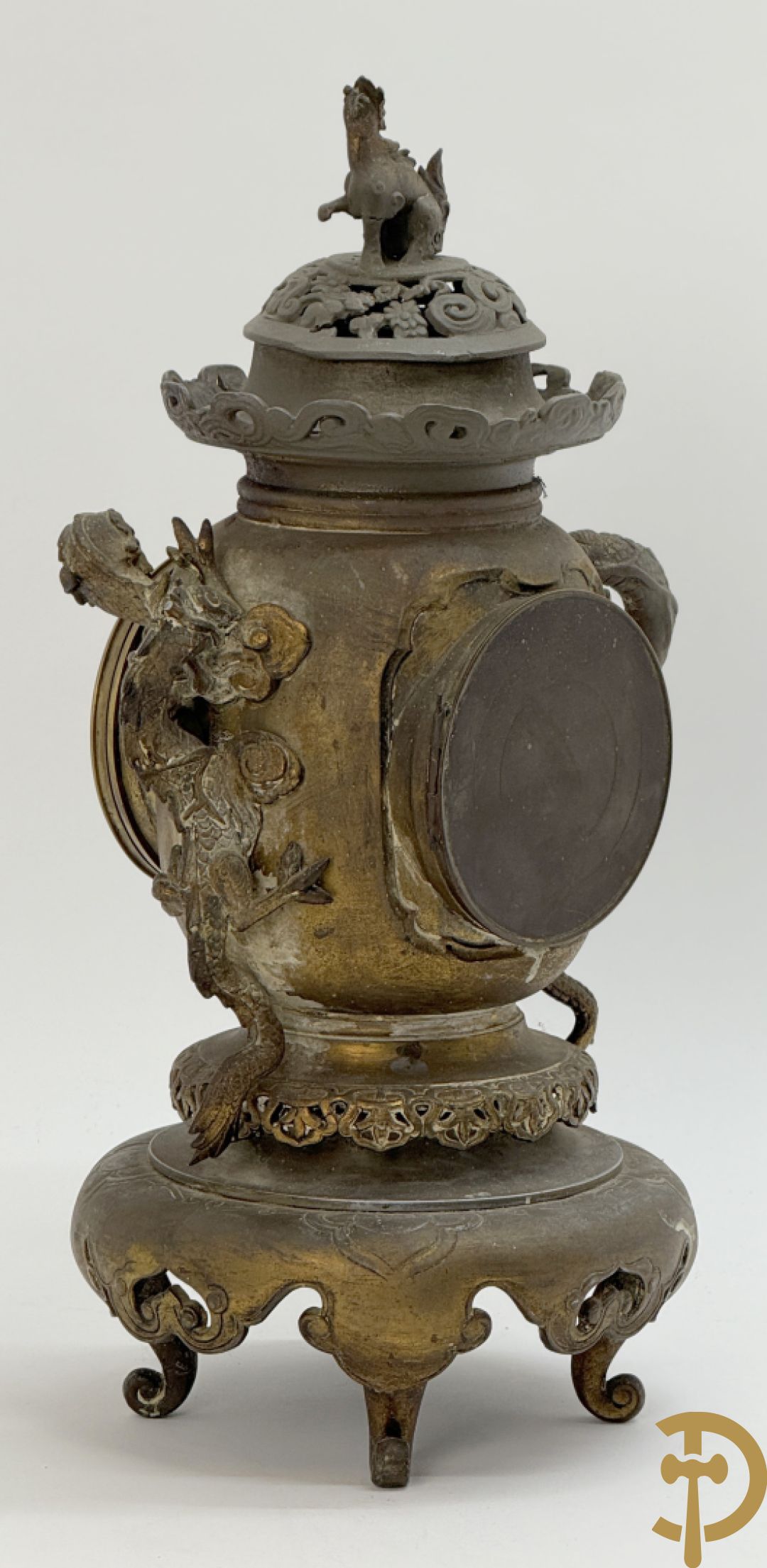 Aziatische pendule in zamak, zijdelings bezet met drakendecor en bovenaan met mythologisch figuur