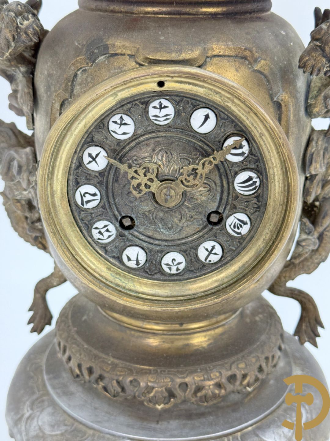 Aziatische pendule in zamak, zijdelings bezet met drakendecor en bovenaan met mythologisch figuur