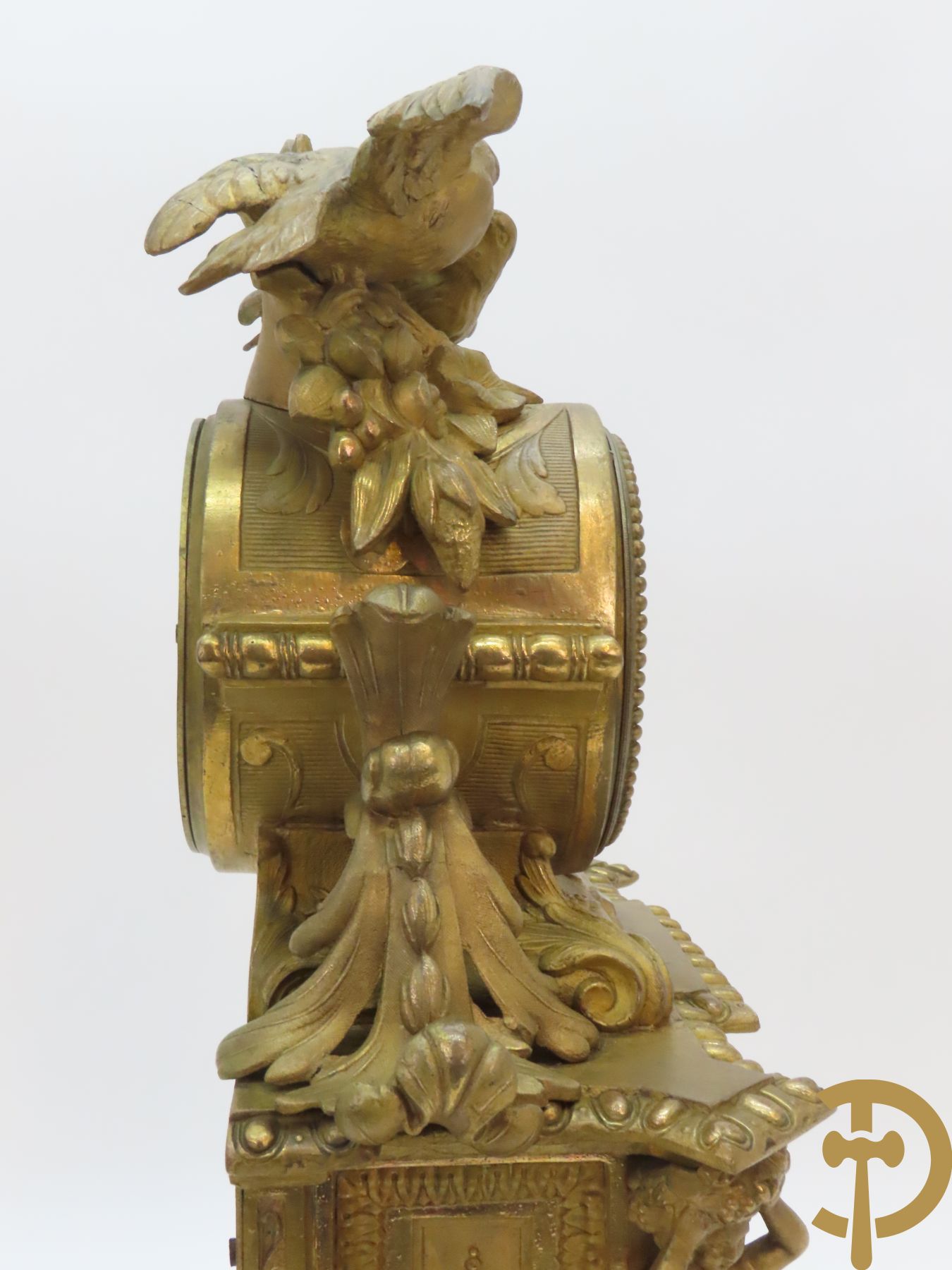 Vergulde pendule in zamak, wijzerplaat bezet met porseleinen plakkettes - bovenaan met vogelpaar, zijdelings met kariathyden houdende een bloementroffee - onder glazen stolp