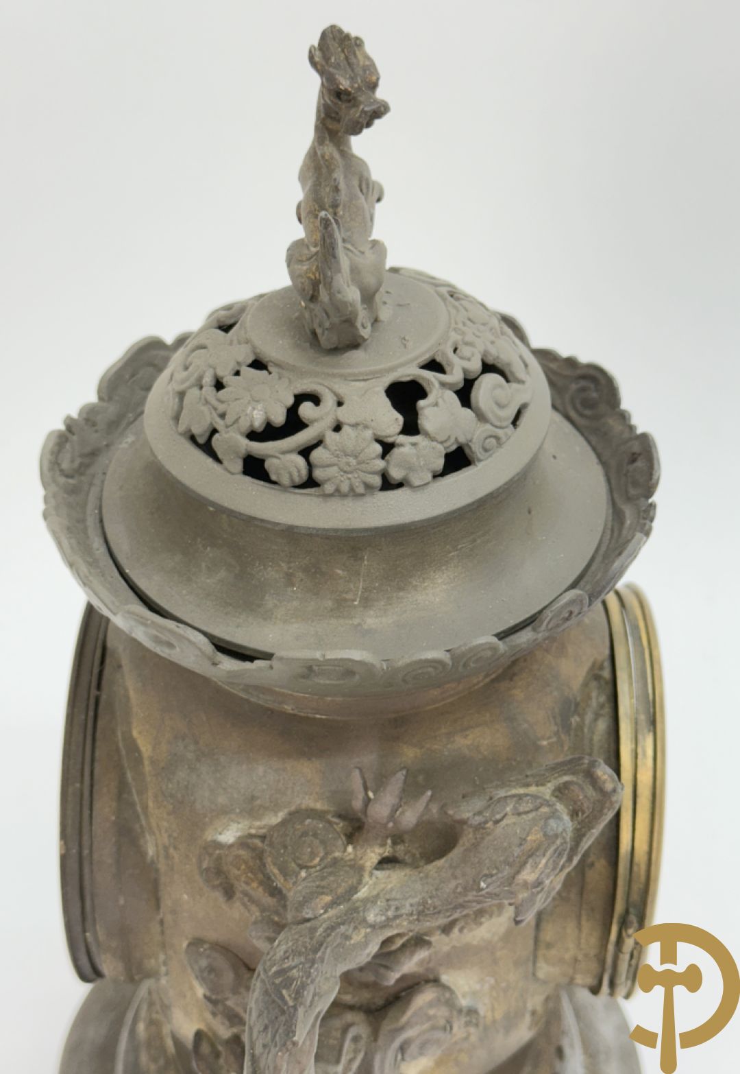 Aziatische pendule in zamak, zijdelings bezet met drakendecor en bovenaan met mythologisch figuur