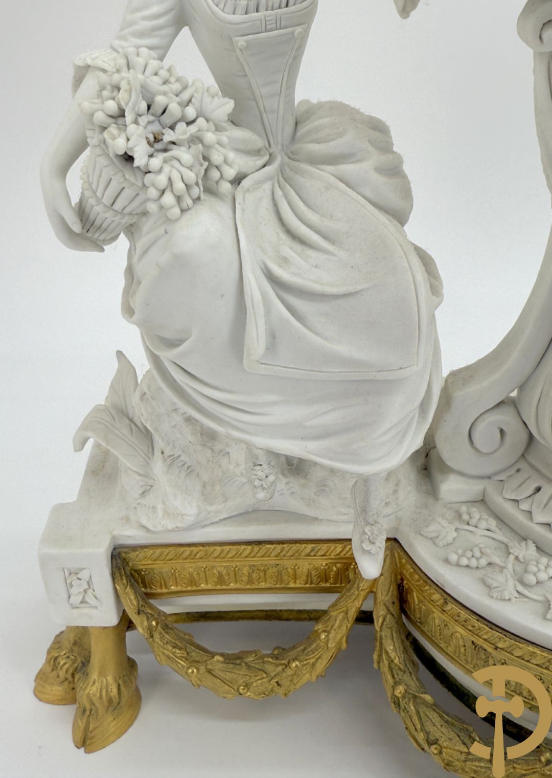 Driedelige porseleinen garnituur met bronsbeslag bestaande uit pendule met dame en amfoor geflankeerd door paar kandelaars bezet met personages