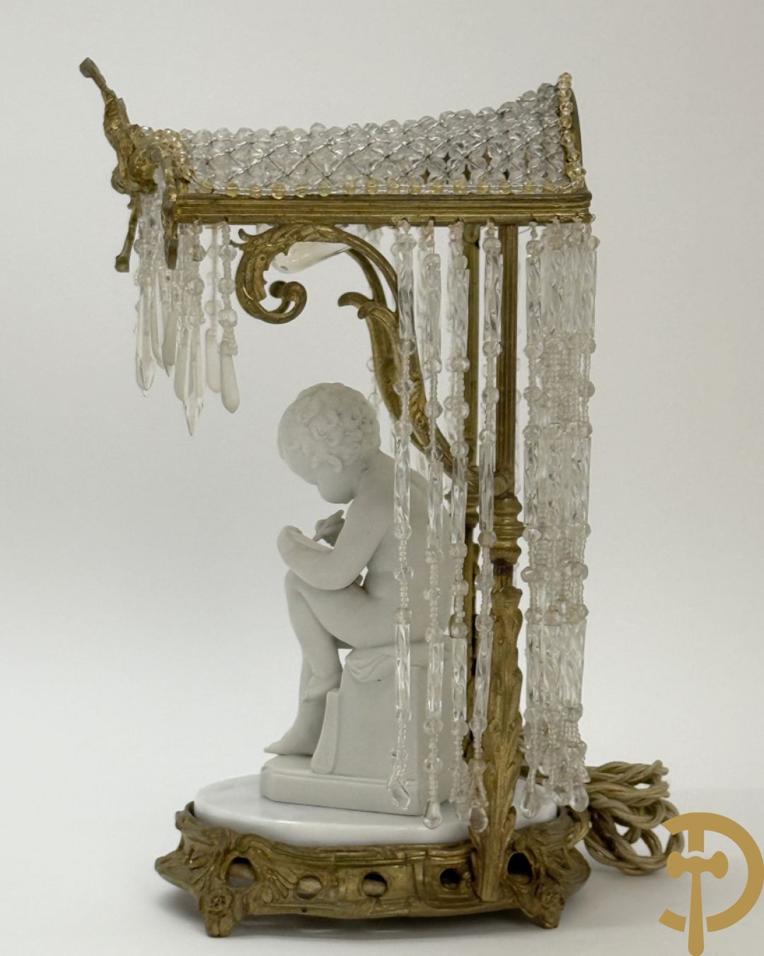 Biscuitbeeld van schrijvende cupido onder bronzen dakje met kristallen bellen bezet - op marmeren sokkel gemonteerd