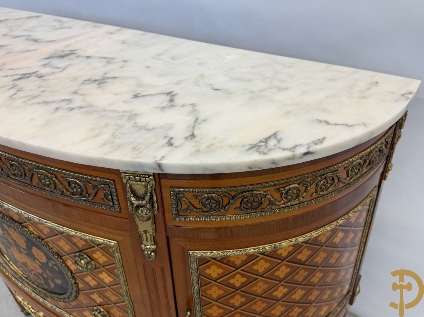 Halve maanvormige drieladencommode met 2 zijdelingse deuren, gemarketteerde bloemenmotieven en bronzen ornamenten, bovenaan bezet met marmeren blad