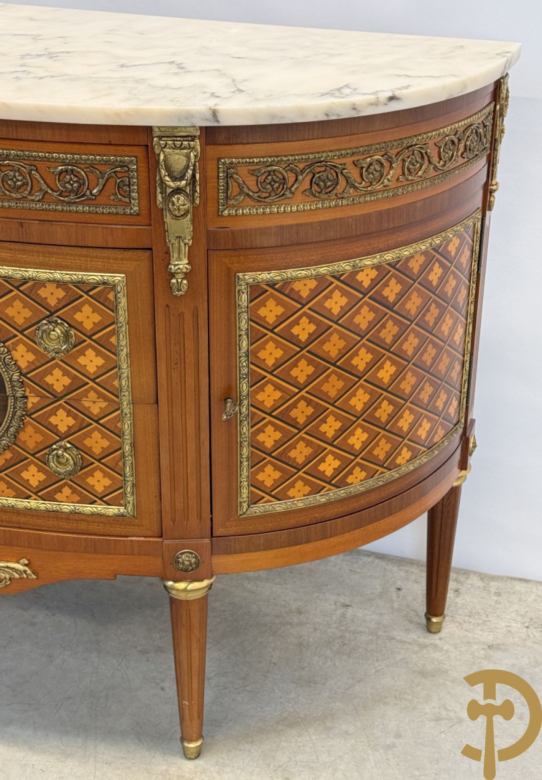 Halve maanvormige drieladencommode met 2 zijdelingse deuren, gemarketteerde bloemenmotieven en bronzen ornamenten, bovenaan bezet met marmeren blad