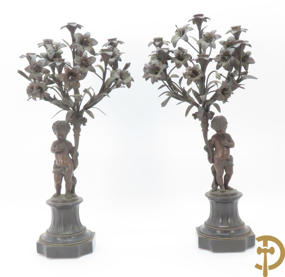 CLODION getekend - Paar elegante bronzen dames met tambour en fruit, geflankeerde door jonge faune, op marmeren klokstel - opgebouwd als garnituur met 2 kandelaars met bronzen kindjes dragende een toorts met bloemen en kaarsen