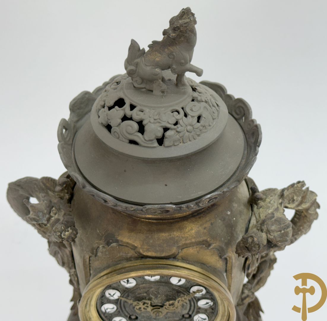 Aziatische pendule in zamak, zijdelings bezet met drakendecor en bovenaan met mythologisch figuur