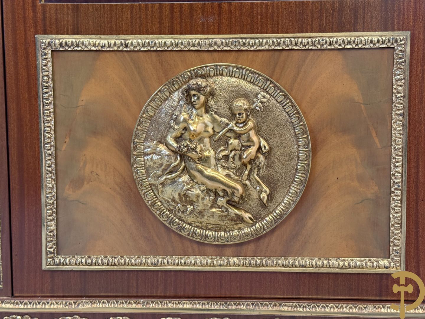 Notelaren vitrine met afgeronde zijkanten, bezet met bronzen plakkettes van dame en cupido