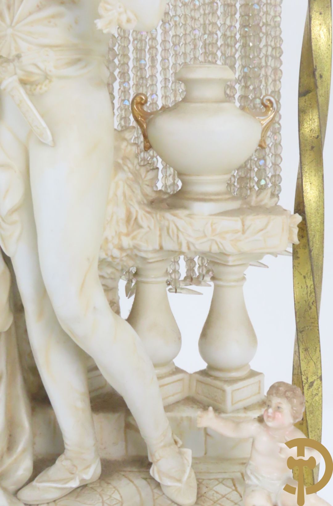 Lieftallig biscuit van romantisch koppel bij amfoor met kleine neergezeten cupido onder koperen baldakijn met kristallen belletjes