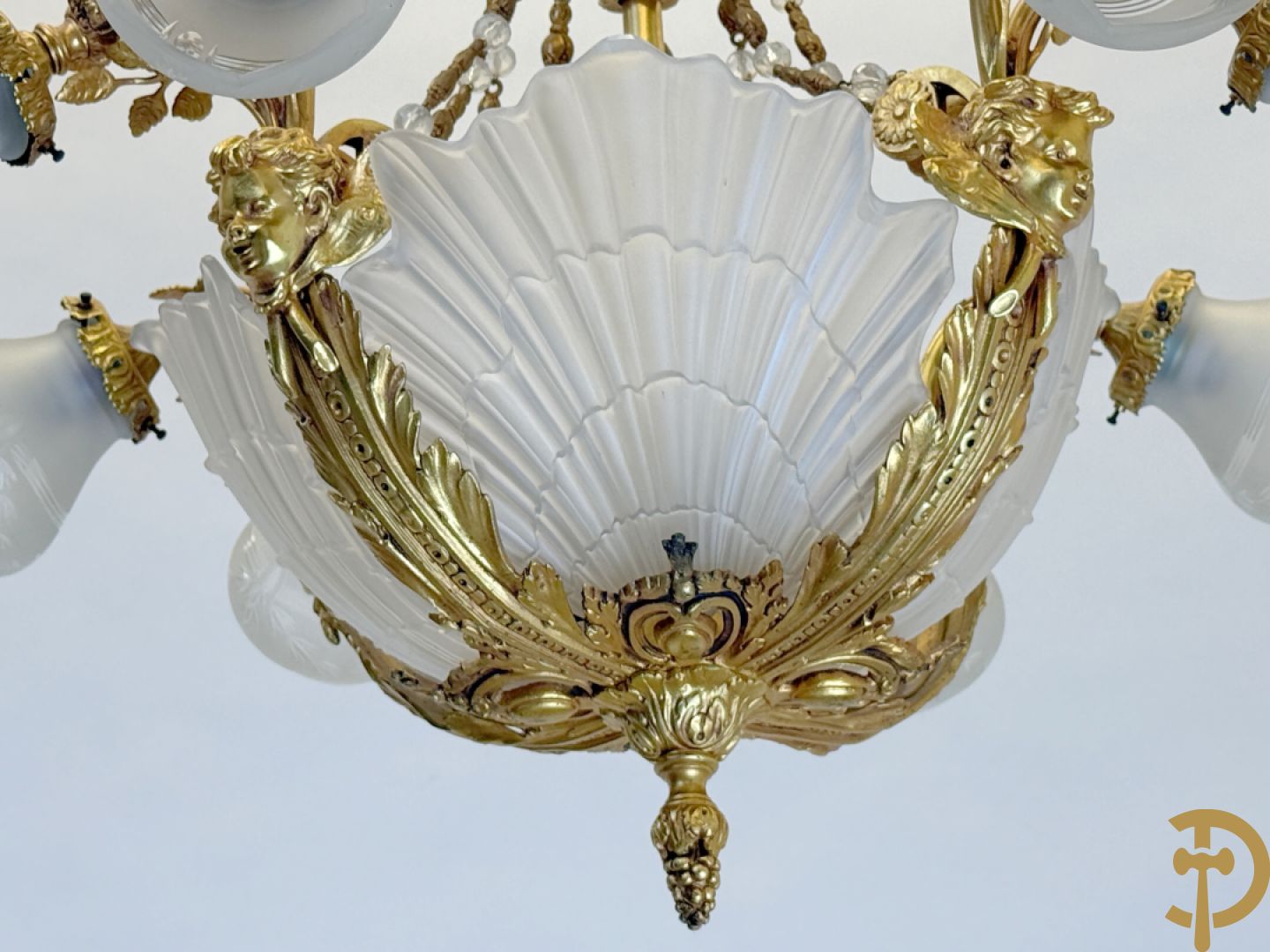 Bronzen vuurvergulde luchter met 4 paar lichtpunten bezet met bladranken, onderaan met glazen schelpen en armen bezet met cupidohoofden