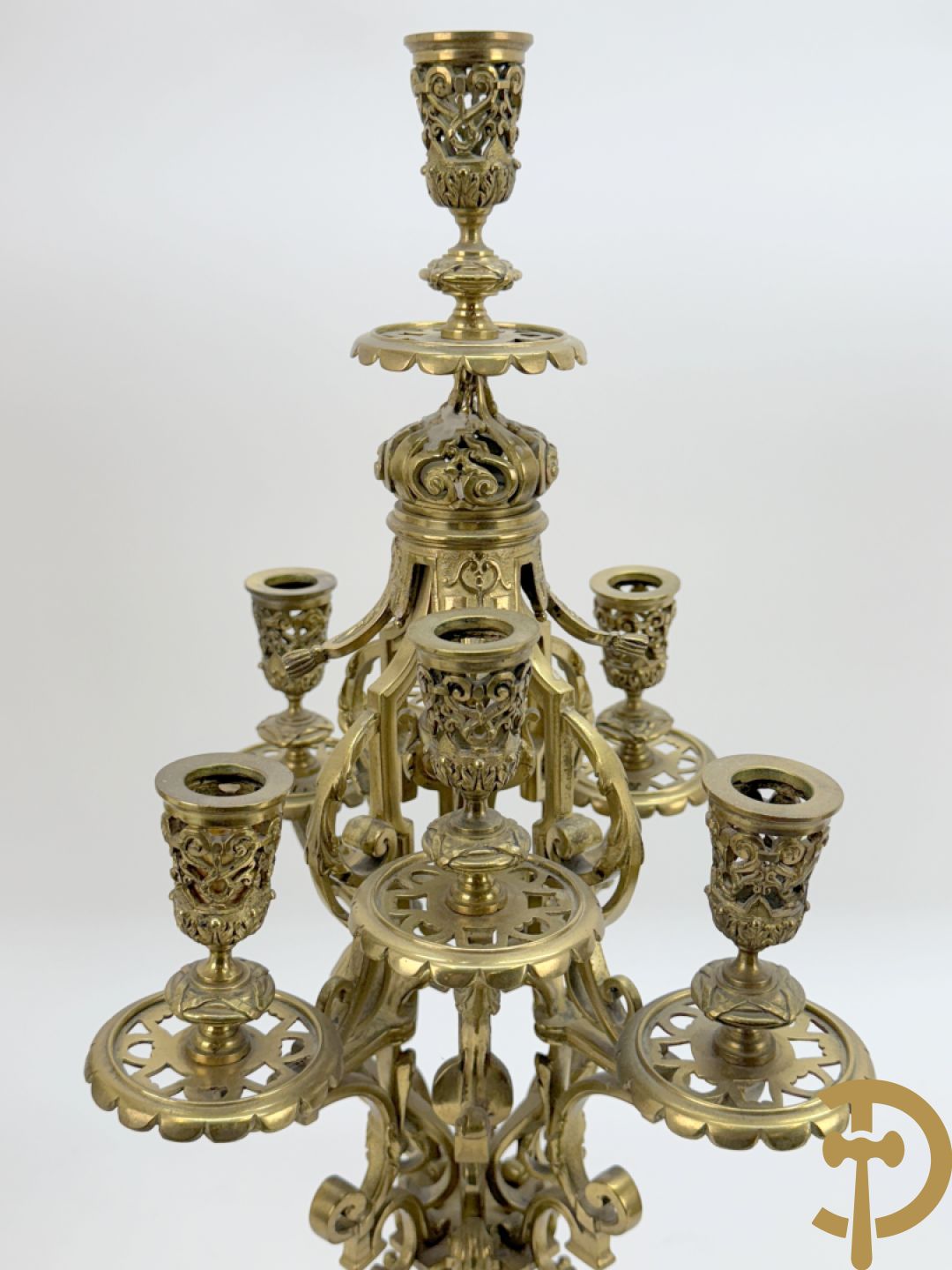 Driedelige bronzen vergulde garntiuur bestaande uit klok met medusahoofden en sfinxen, geflankeerd door paar zevenarmige kandelaars met accanthusranken en sfinxen