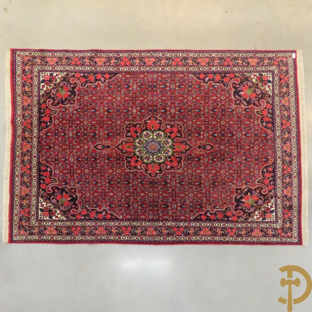 Oosters handgeknoopt tapijt met bloemenpatronen op rode fond