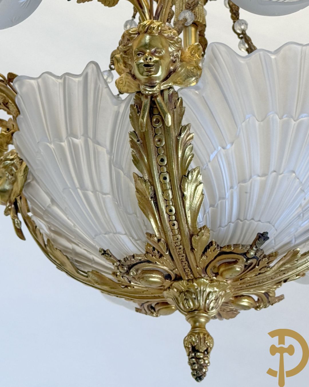 Bronzen vuurvergulde luchter met 4 paar lichtpunten bezet met bladranken, onderaan met glazen schelpen en armen bezet met cupidohoofden