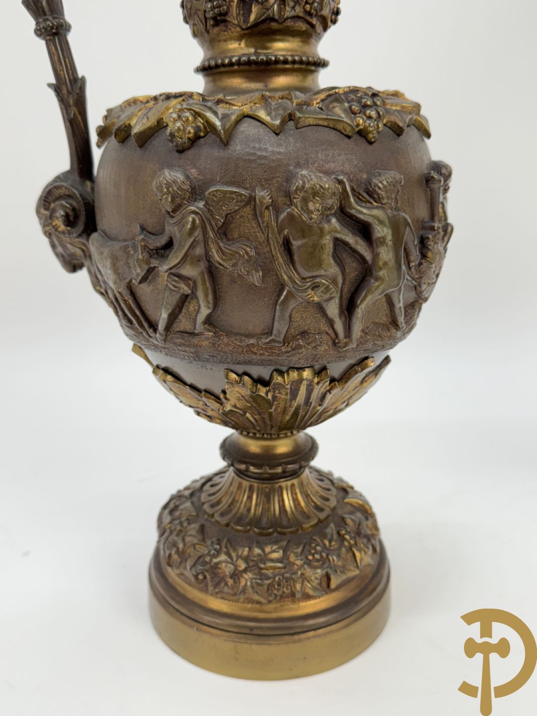 Paar bronzen schenkkannen met basrelief van putti en accanthusranken