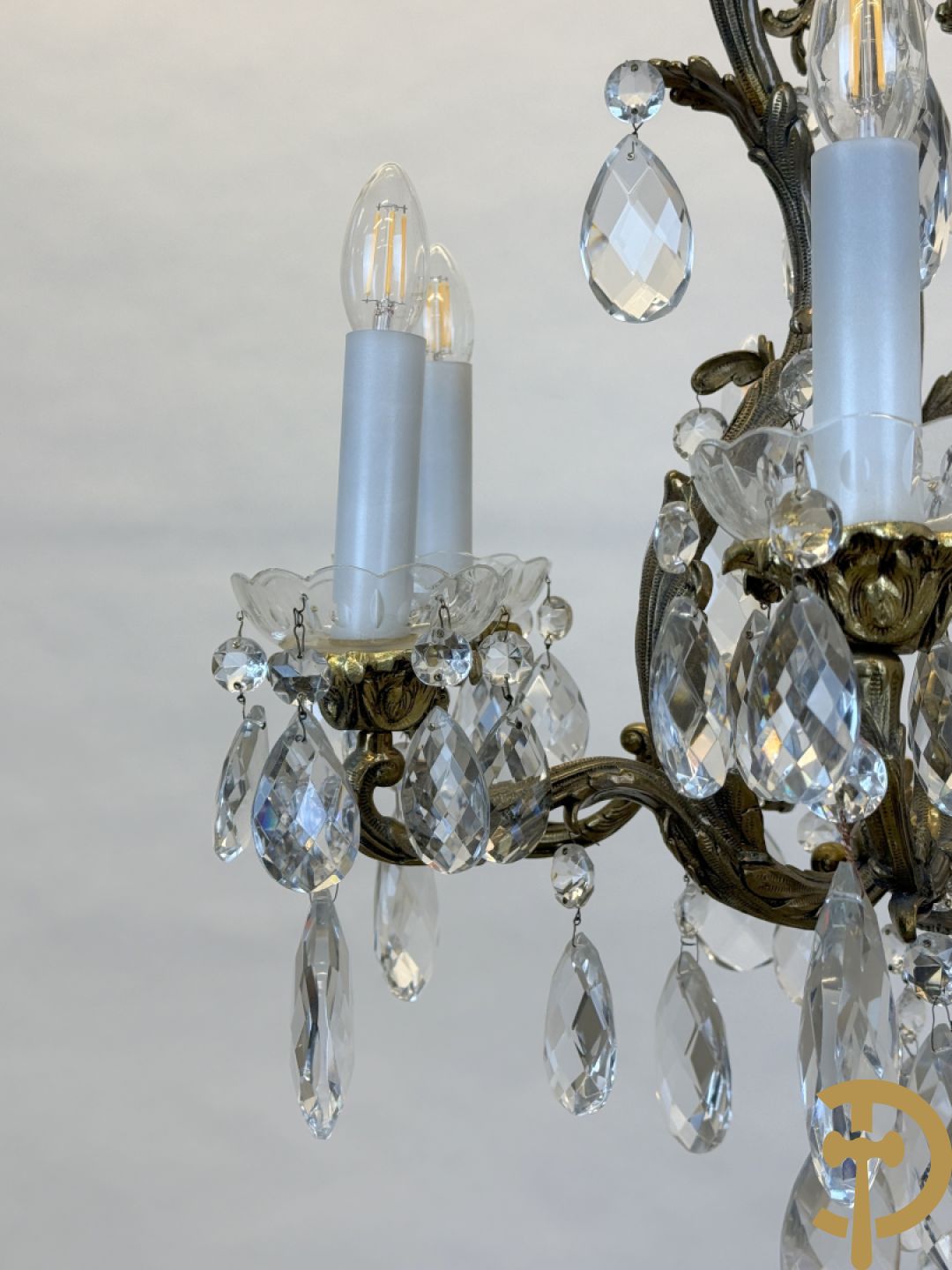 Achtarmige koperen luchter met kristallen bellen en binnenin met pinakel bezet