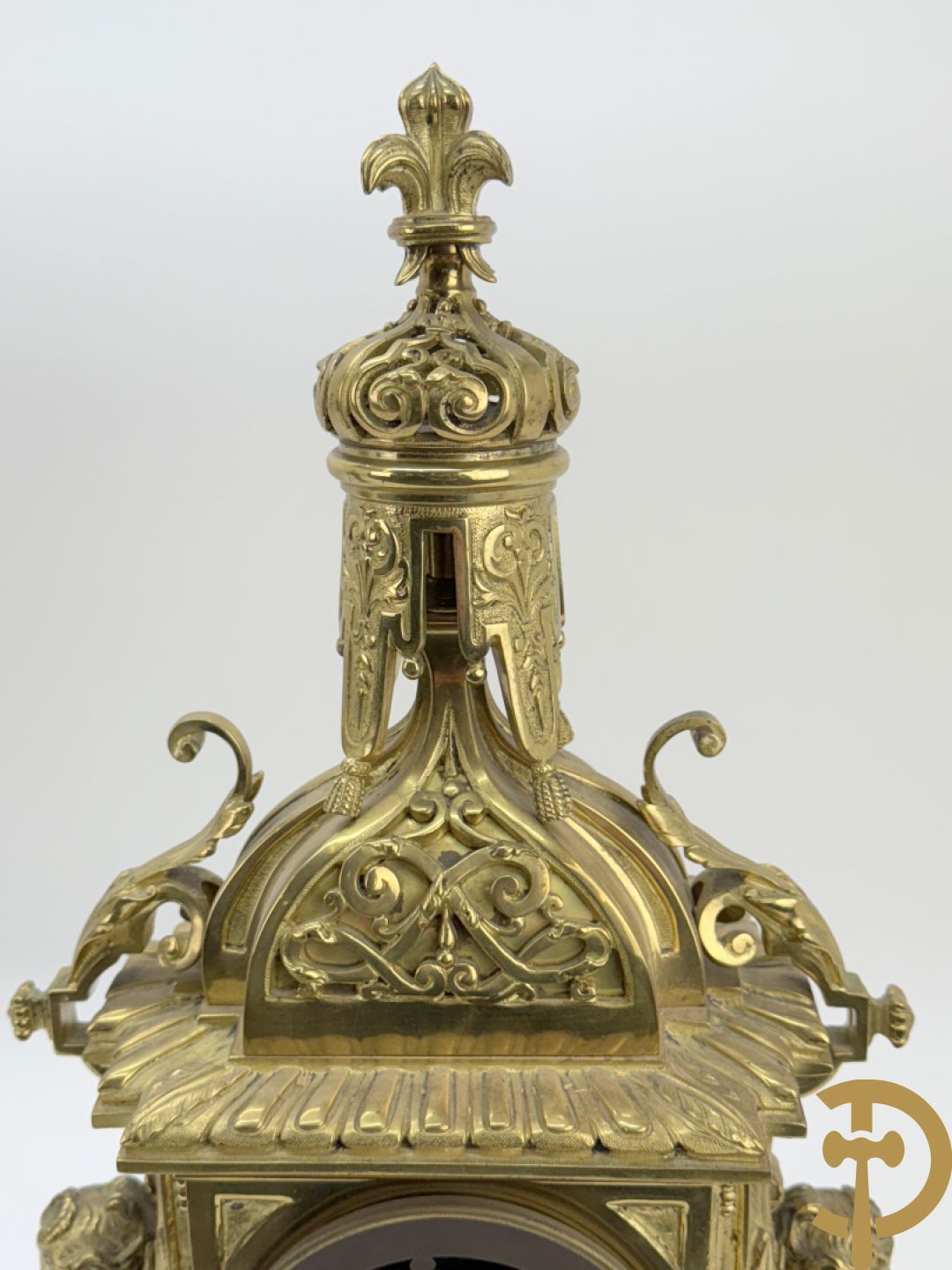 Driedelige bronzen vergulde garntiuur bestaande uit klok met medusahoofden en sfinxen, geflankeerd door paar zevenarmige kandelaars met accanthusranken en sfinxen