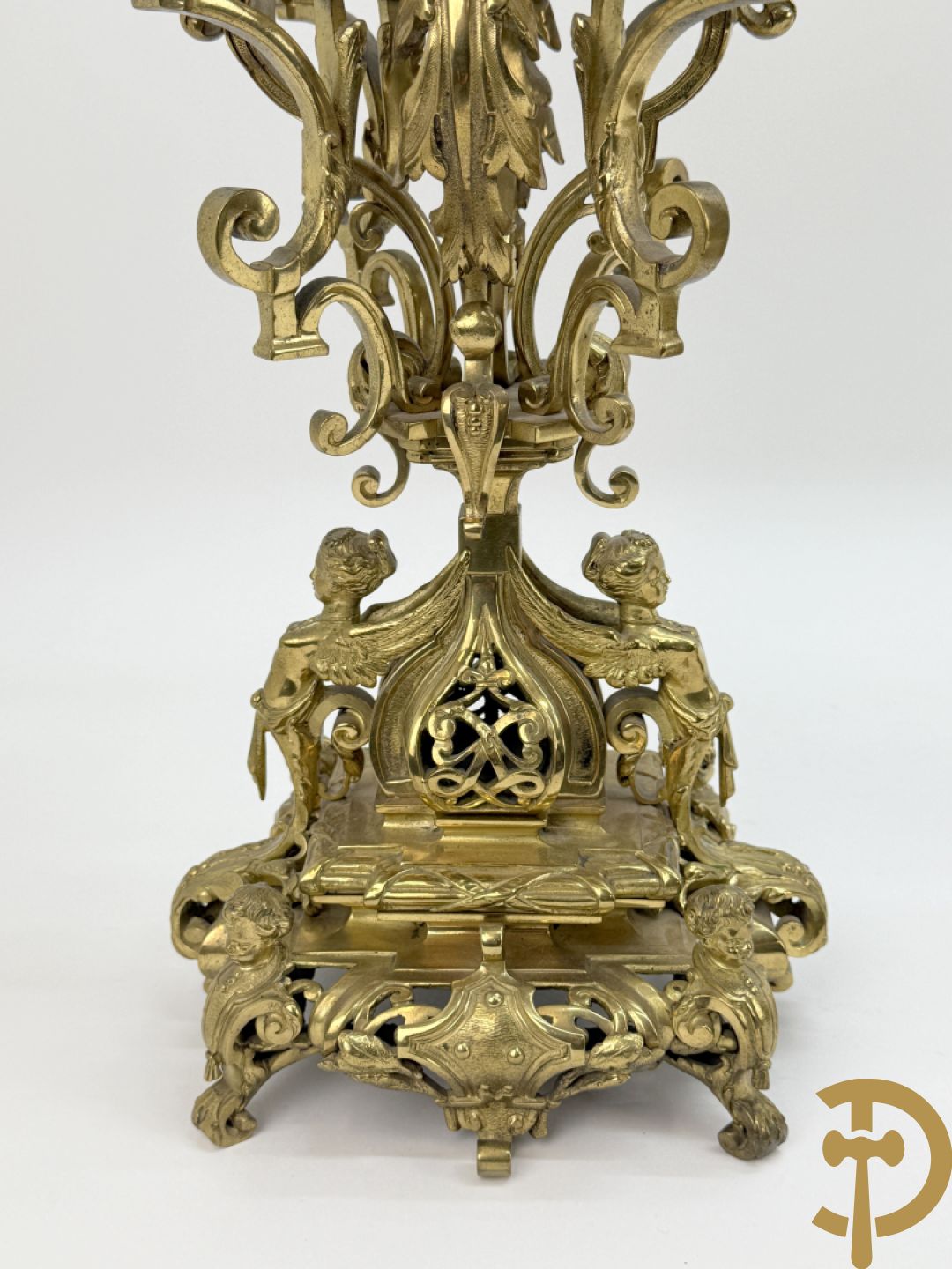 Driedelige bronzen vergulde garntiuur bestaande uit klok met medusahoofden en sfinxen, geflankeerd door paar zevenarmige kandelaars met accanthusranken en sfinxen