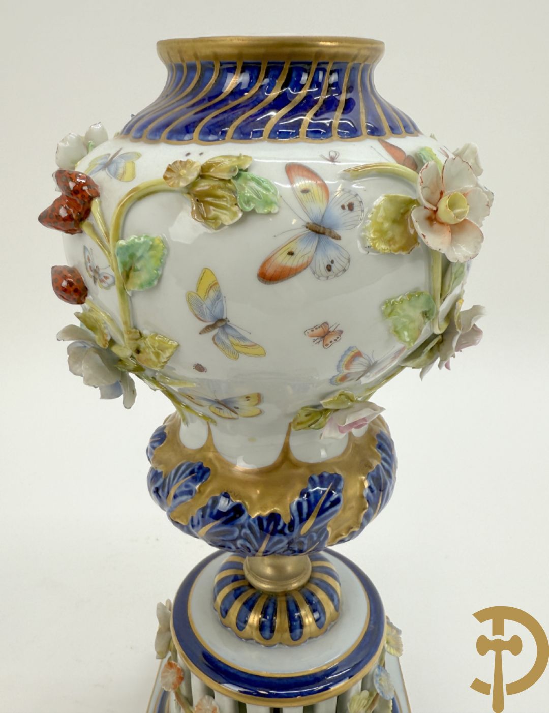 Porseleinen siervaas met handbeschilderd geanimeerd decor bezet met basrelief van bloemen en bovenaan bekroond met deksel met vogel