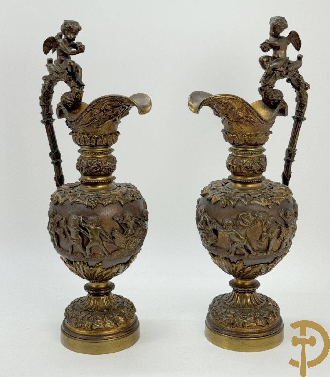 Paar bronzen schenkkannen met basrelief van putti en accanthusranken