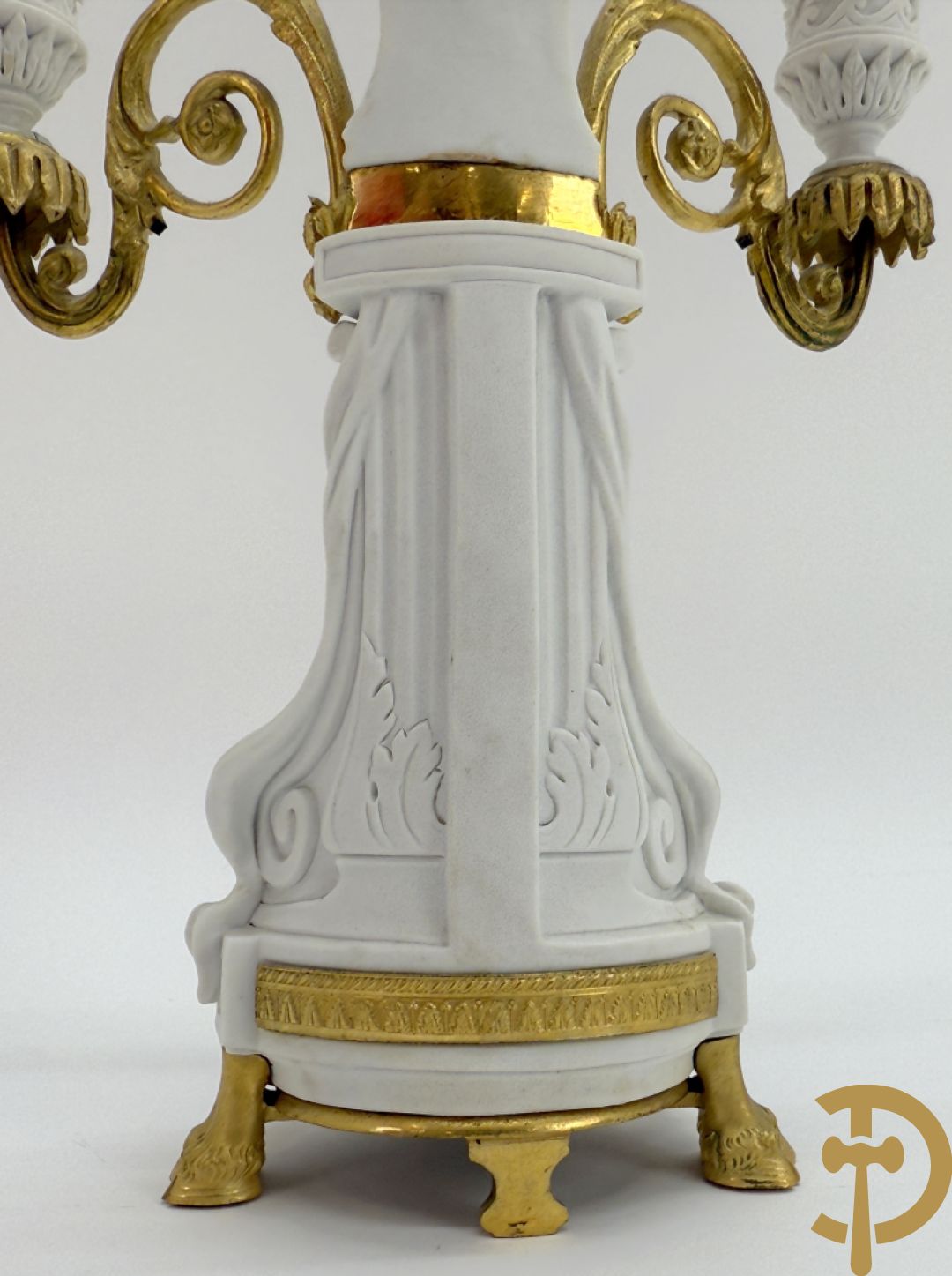 Driedelige porseleinen garnituur met bronsbeslag bestaande uit pendule met dame en amfoor geflankeerd door paar kandelaars bezet met personages