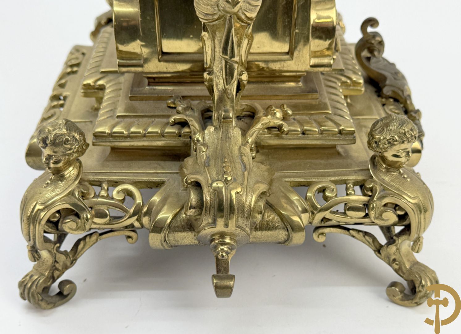 Driedelige bronzen vergulde garntiuur bestaande uit klok met medusahoofden en sfinxen, geflankeerd door paar zevenarmige kandelaars met accanthusranken en sfinxen
