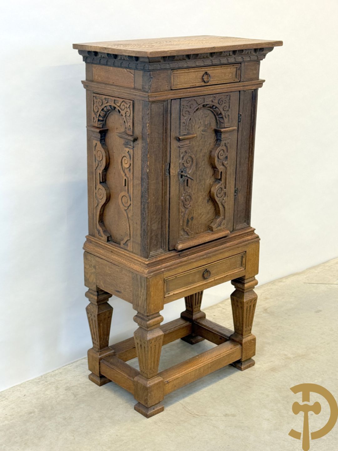 Massief eiken ééndeurskast op onderstel met lade bovenaan, lade onderaan, sculptuur in zijkant en deur