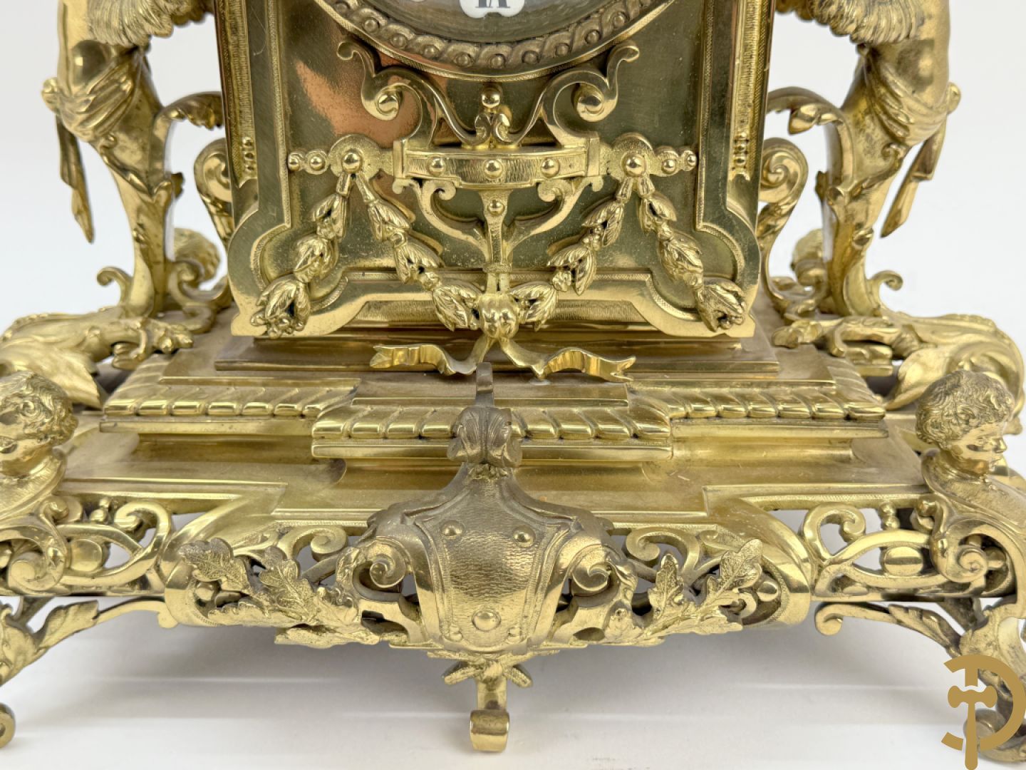 Driedelige bronzen vergulde garntiuur bestaande uit klok met medusahoofden en sfinxen, geflankeerd door paar zevenarmige kandelaars met accanthusranken en sfinxen