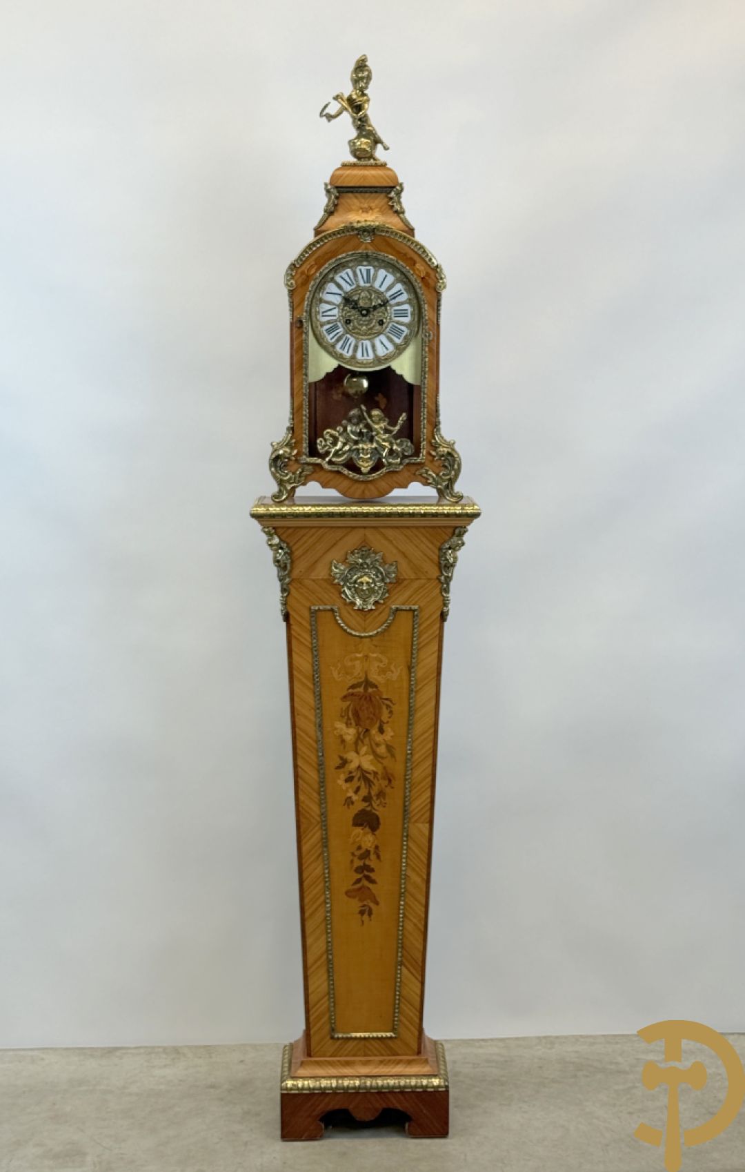 Notelaren pendule met bloemenmarquetterie en bronsbeslag, bovenaan bekroond met bronzen figuur - met bijhorende sokkel in notelaar met bronsbeslag