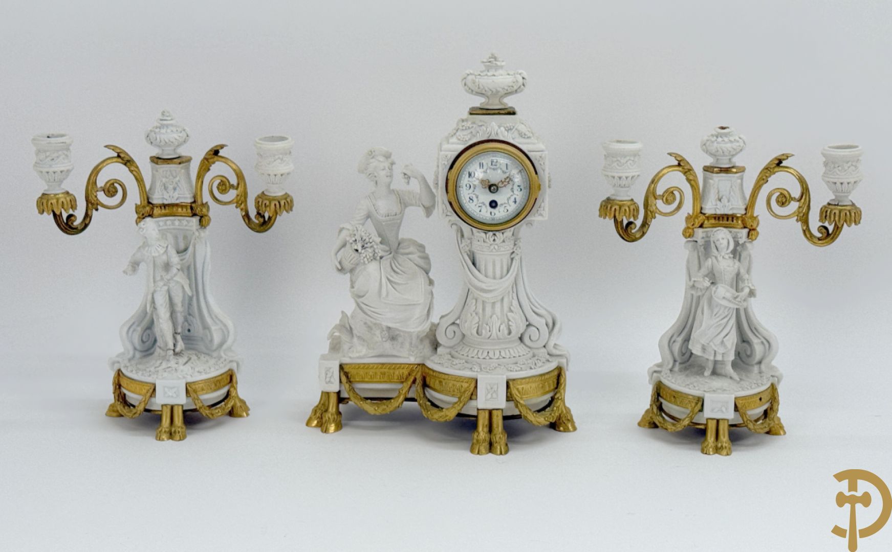 Driedelige porseleinen garnituur met bronsbeslag bestaande uit pendule met dame en amfoor geflankeerd door paar kandelaars bezet met personages