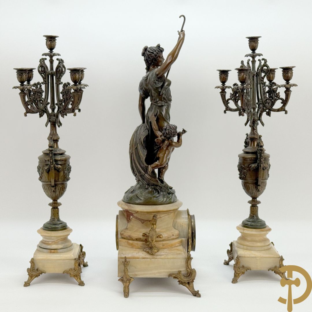 Driedelige zamak garnituur bestaande uit pendule met cupido en dame geflankeerd door paar vijfarmige kandelaars, Bruchon getekend