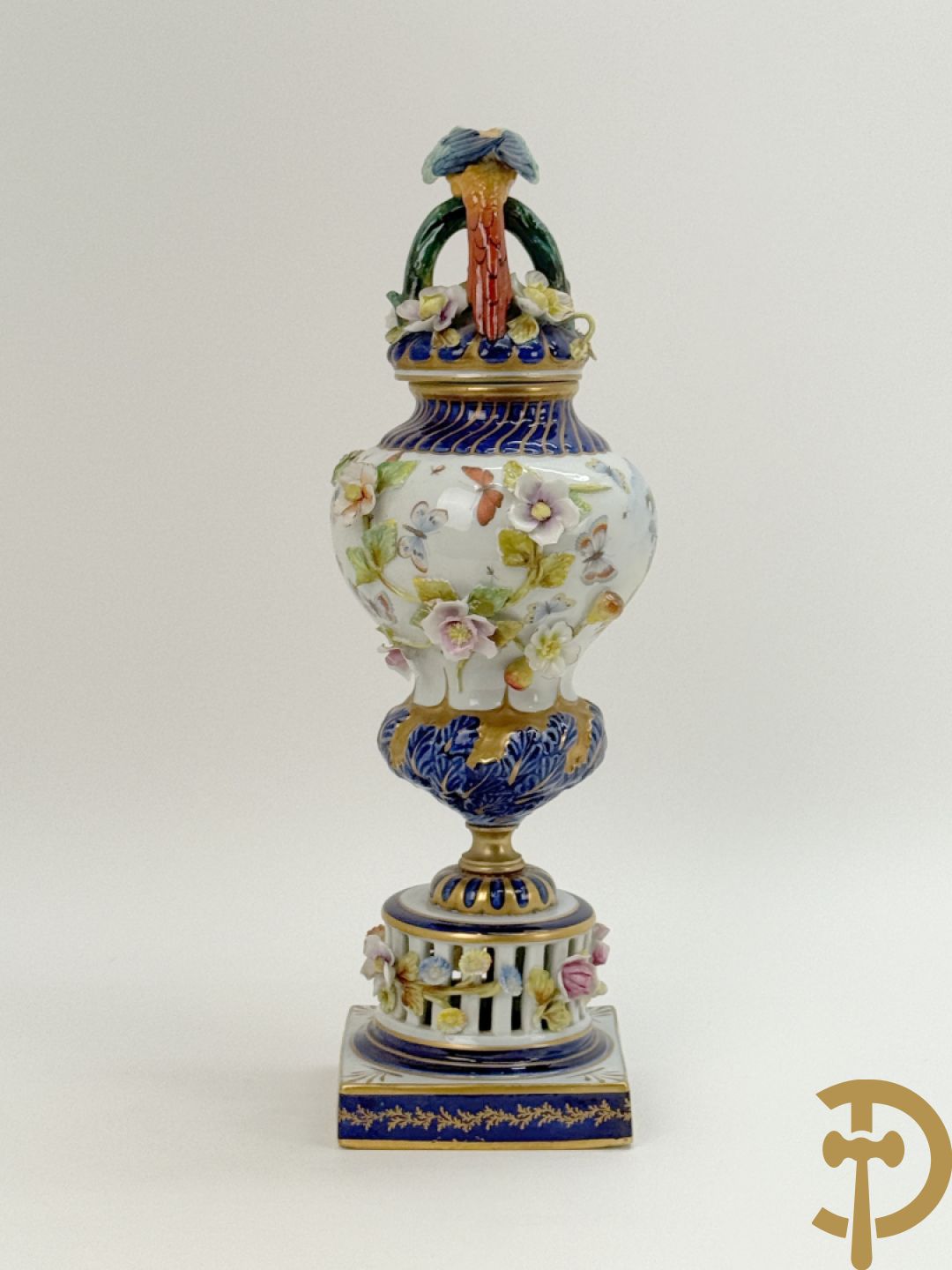 Porseleinen siervaas met handbeschilderd geanimeerd decor bezet met basrelief van bloemen en bovenaan bekroond met deksel met vogel