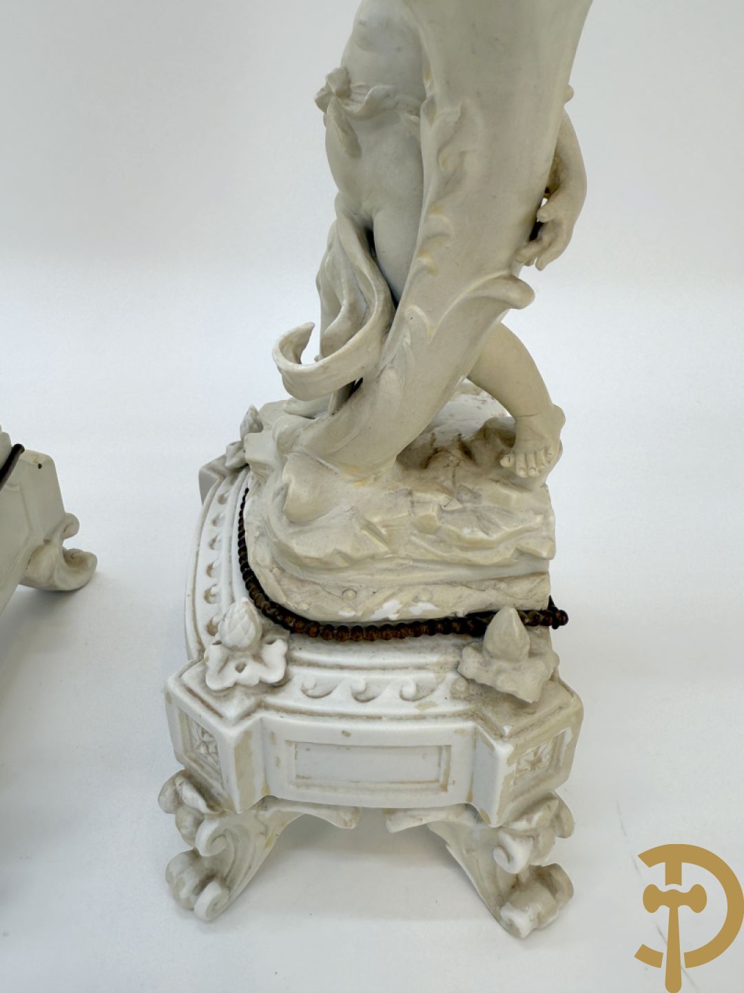 Driedelige porseleinen garnituur bestaande uit pendule bezet met lieftallig koppel, geflankeerd door paar kandelaars met cupido