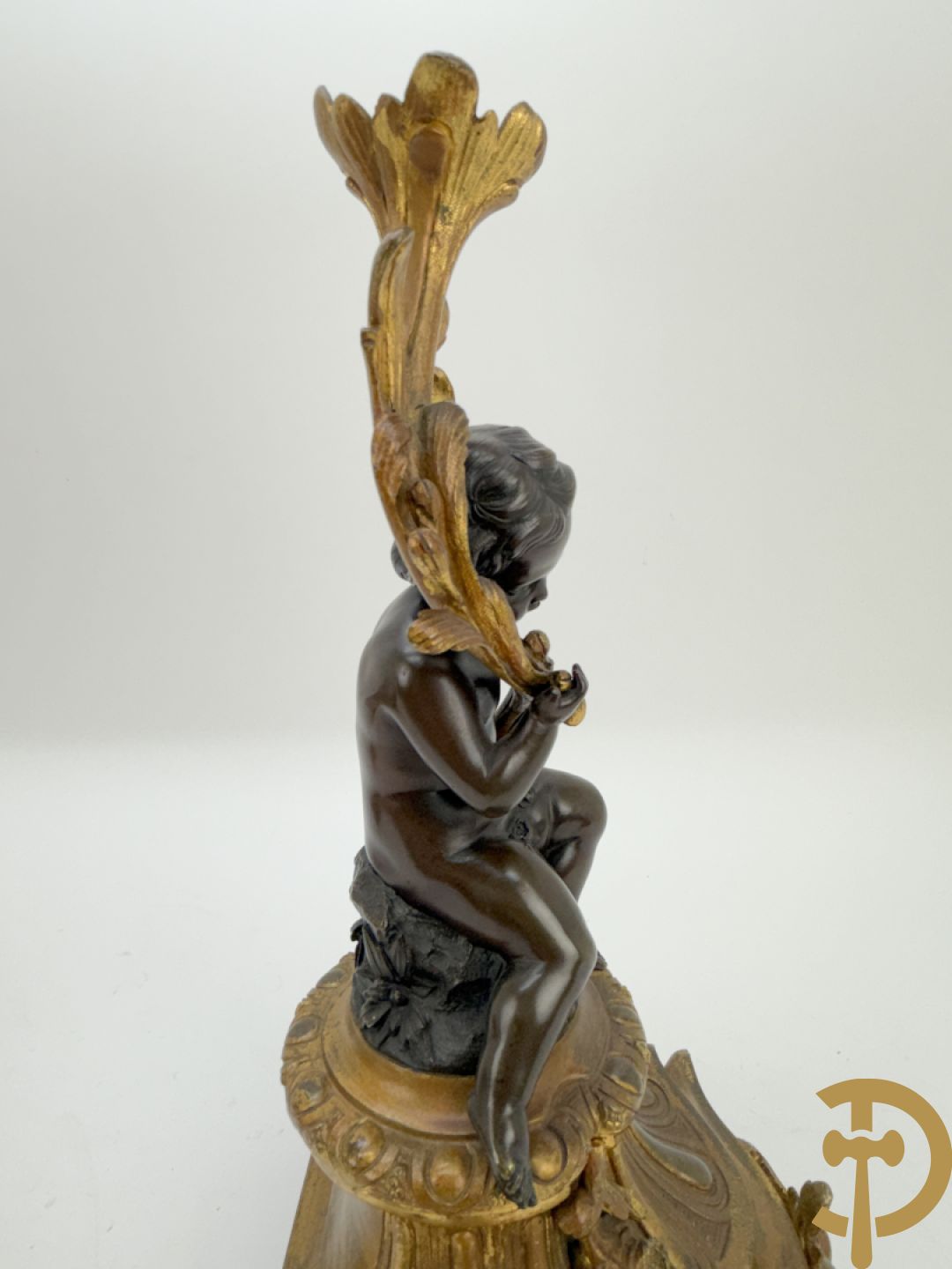 Driedelige bronzen garnituur bestaande uit middenstuk met bronzen vuurvergulde klok, Daubrée gemerkt à Nancy, bovenaan bekroond met Cleopatra met drinkbeker - getekend van Cumberworth sculpteur - geflankeerd door paar cupido