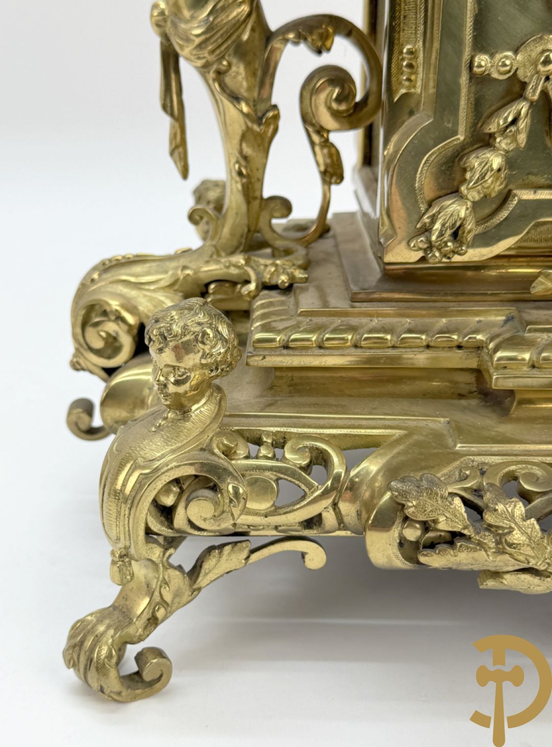 Driedelige bronzen vergulde garntiuur bestaande uit klok met medusahoofden en sfinxen, geflankeerd door paar zevenarmige kandelaars met accanthusranken en sfinxen