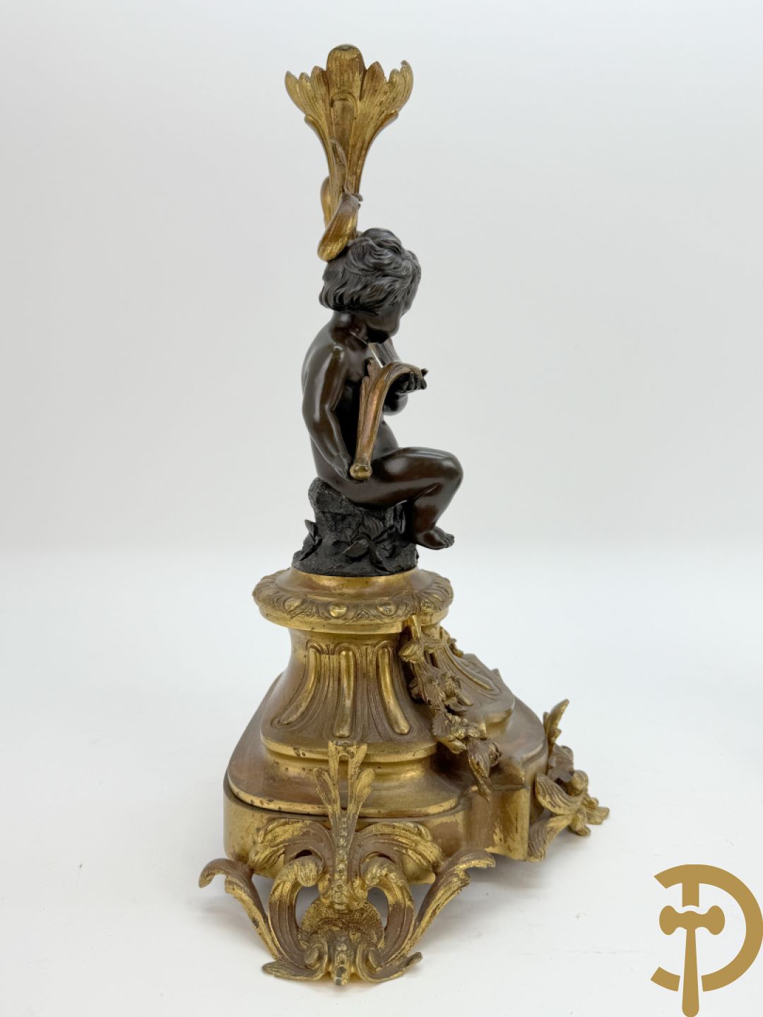 Driedelige bronzen garnituur bestaande uit middenstuk met bronzen vuurvergulde klok, Daubrée gemerkt à Nancy, bovenaan bekroond met Cleopatra met drinkbeker - getekend van Cumberworth sculpteur - geflankeerd door paar cupido