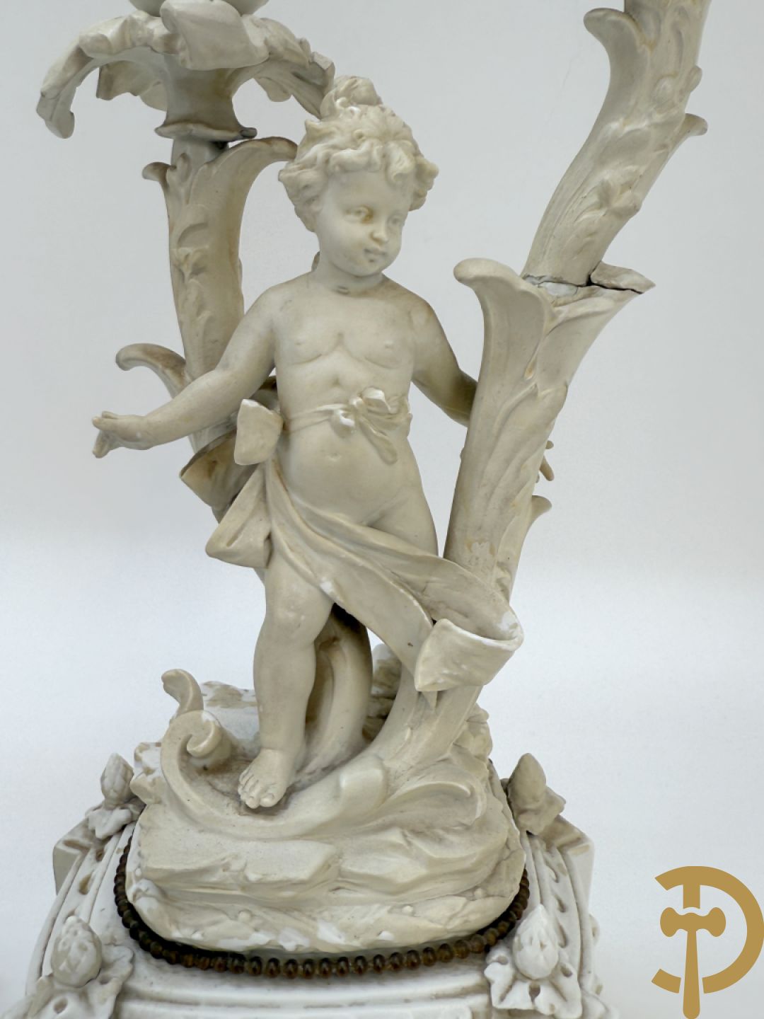 Driedelige porseleinen garnituur bestaande uit pendule bezet met lieftallig koppel, geflankeerd door paar kandelaars met cupido