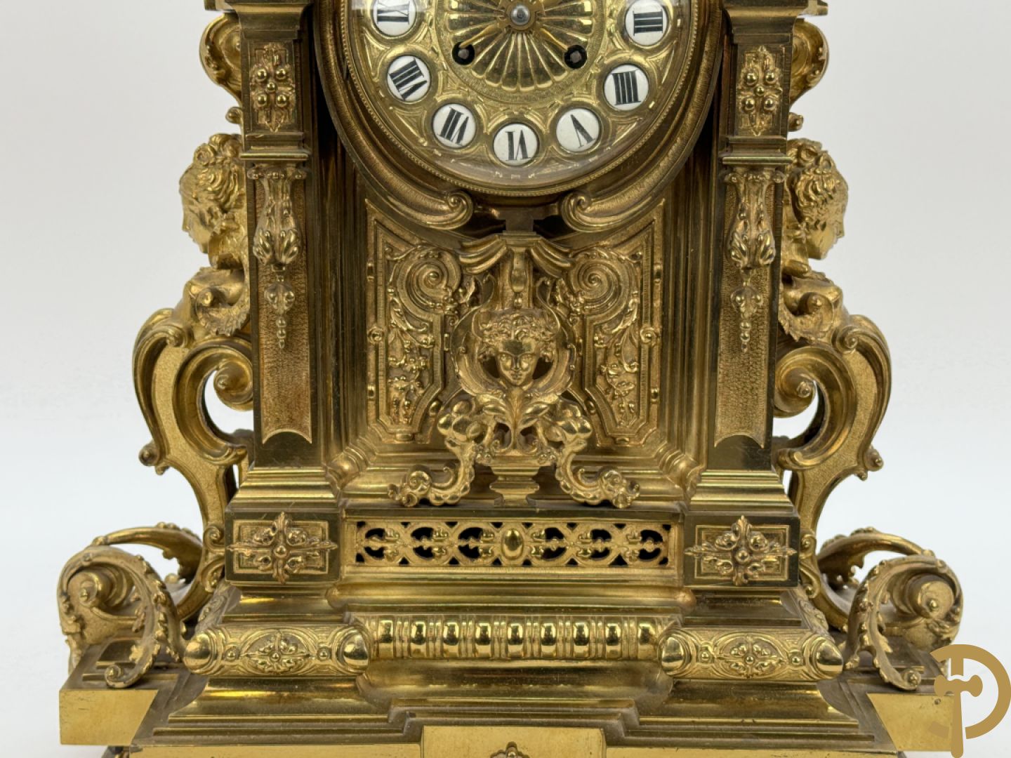 Vuurvergulde bronzen pendule, zijdelings bezet met gevleugelde dames, bovenaan met amfoor