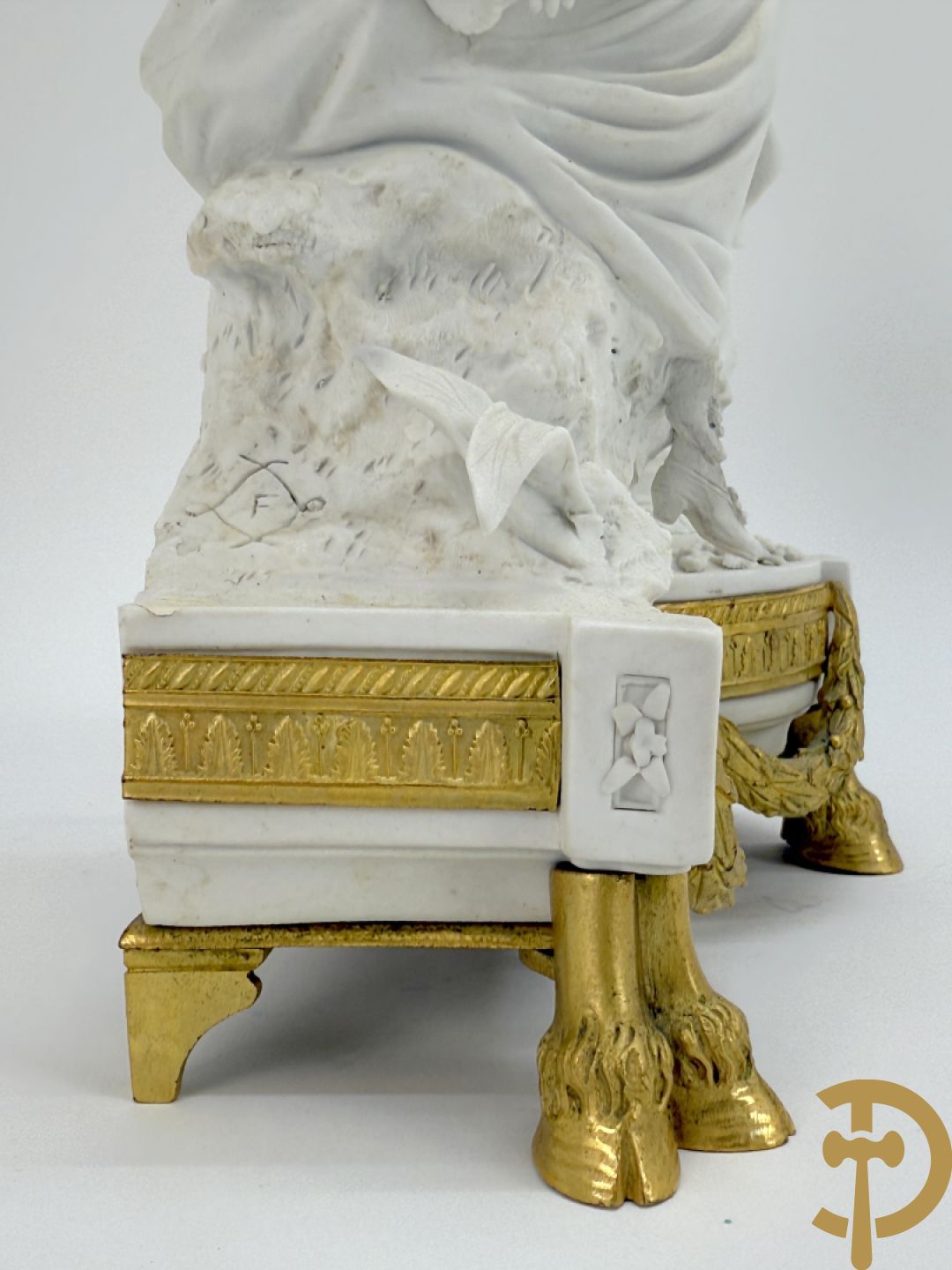 Driedelige porseleinen garnituur met bronsbeslag bestaande uit pendule met dame en amfoor geflankeerd door paar kandelaars bezet met personages