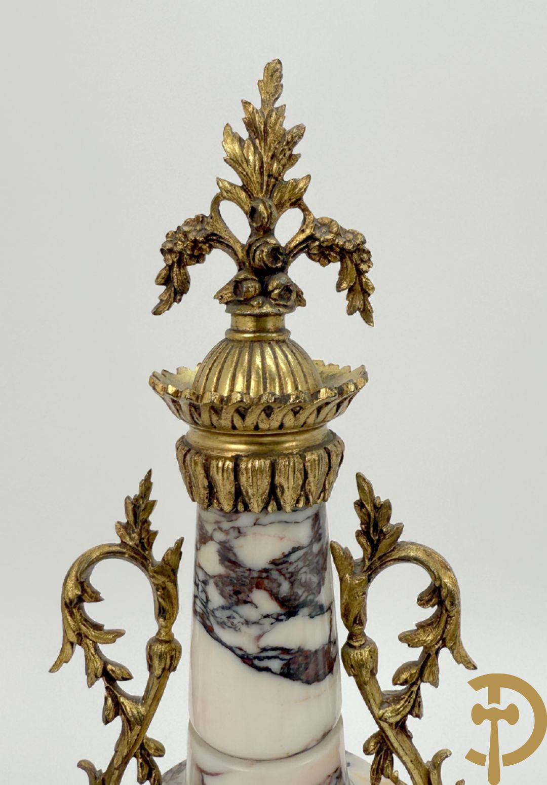 Driedelige wit marmeren garnituur bestaande uit vierzuilenpendule met bloemen en troffee geflankeerd door paar cassolettes met ramskoppen bezet