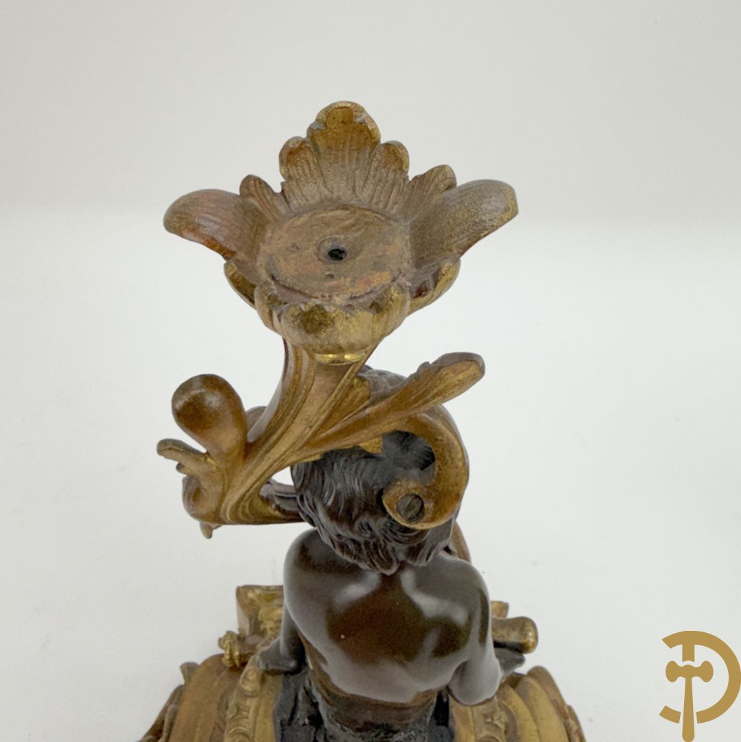 Driedelige bronzen garnituur bestaande uit middenstuk met bronzen vuurvergulde klok, Daubrée gemerkt à Nancy, bovenaan bekroond met Cleopatra met drinkbeker - getekend van Cumberworth sculpteur - geflankeerd door paar cupido