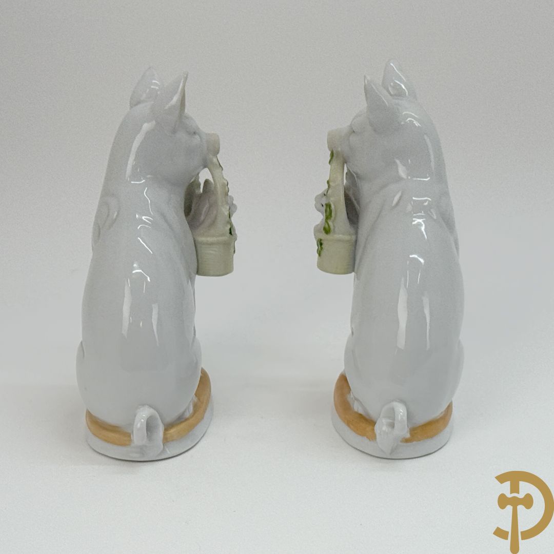 Koppel porseleinen beeldjes met varkens houdende een mandje met biggetjes