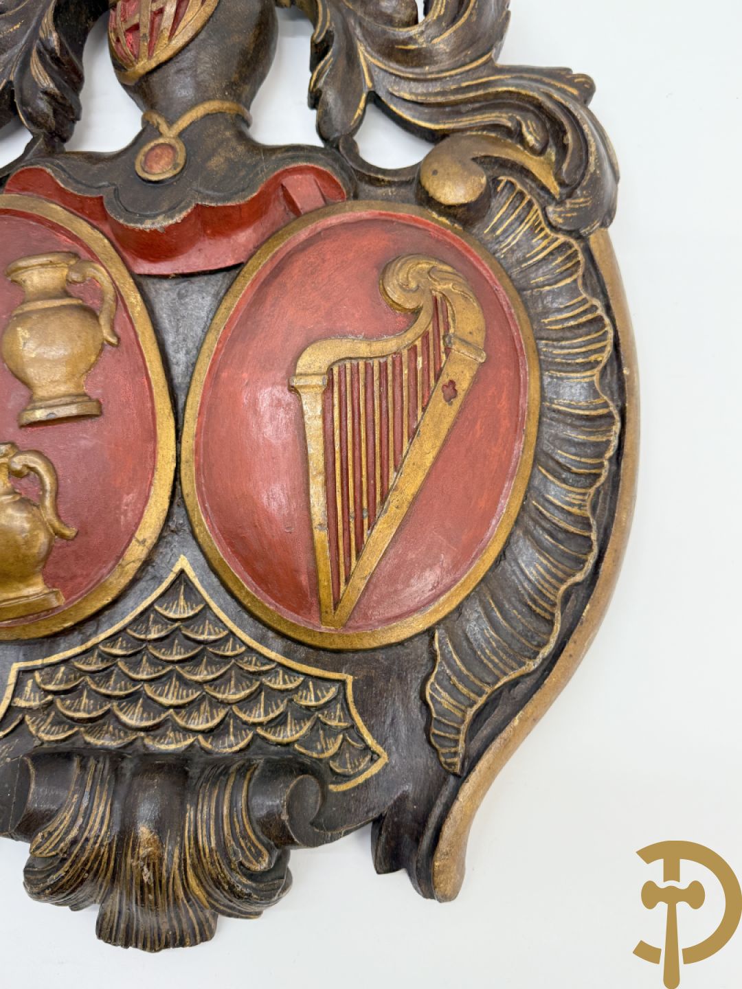 Houtgesculpteerd wapenschild met cartouche bovenaan en embleem met kannen en harp