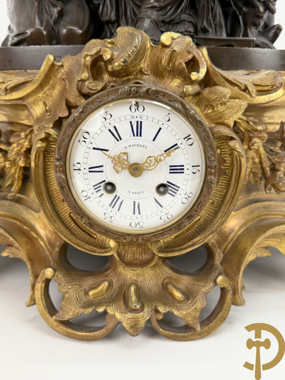 Driedelige bronzen garnituur bestaande uit middenstuk met bronzen vuurvergulde klok, Daubrée gemerkt à Nancy, bovenaan bekroond met Cleopatra met drinkbeker - getekend van Cumberworth sculpteur - geflankeerd door paar cupido