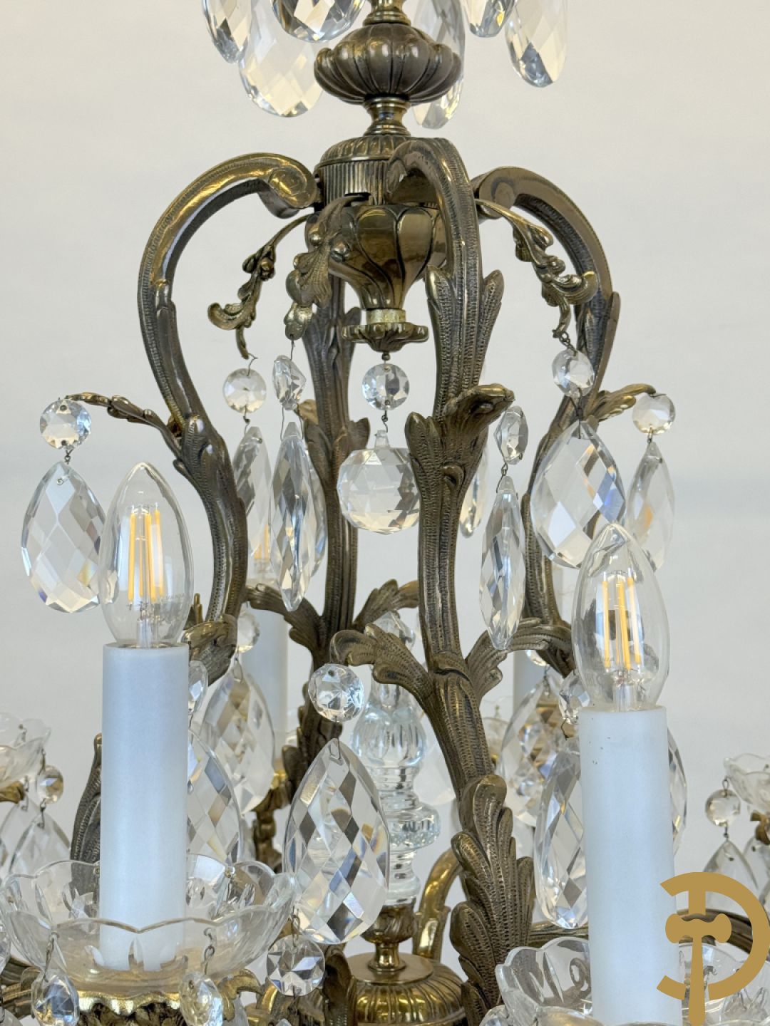 Achtarmige koperen luchter met kristallen bellen en binnenin met pinakel bezet