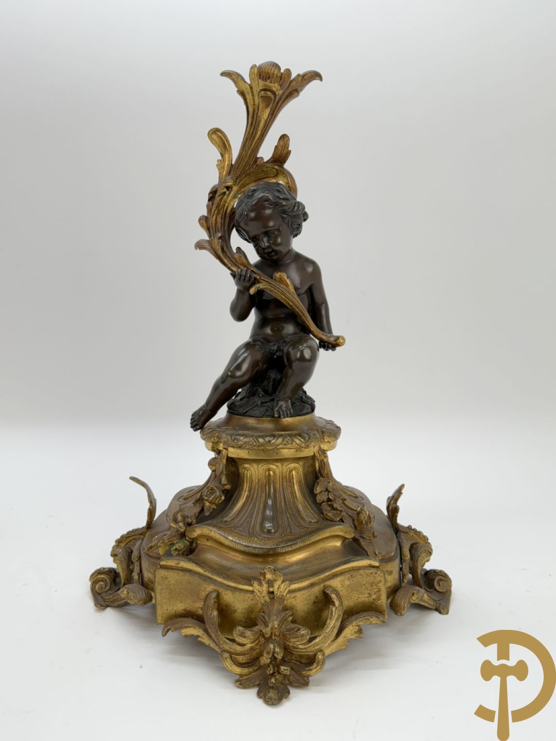 Driedelige bronzen garnituur bestaande uit middenstuk met bronzen vuurvergulde klok, Daubrée gemerkt à Nancy, bovenaan bekroond met Cleopatra met drinkbeker - getekend van Cumberworth sculpteur - geflankeerd door paar cupido