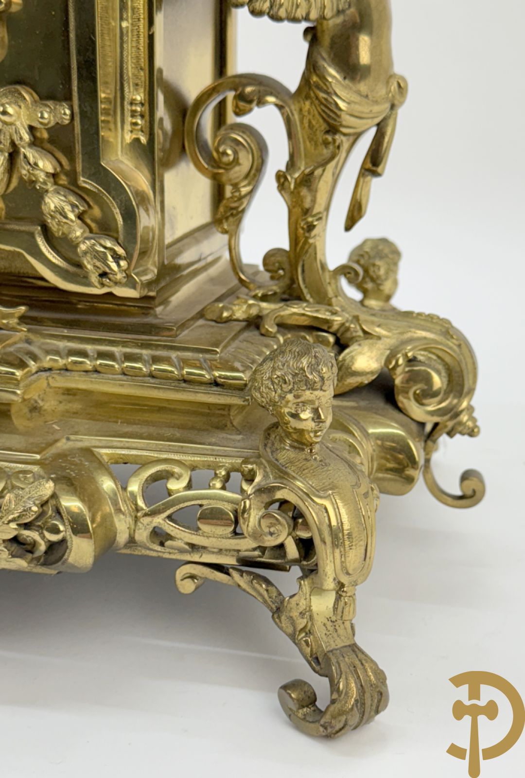 Driedelige bronzen vergulde garntiuur bestaande uit klok met medusahoofden en sfinxen, geflankeerd door paar zevenarmige kandelaars met accanthusranken en sfinxen