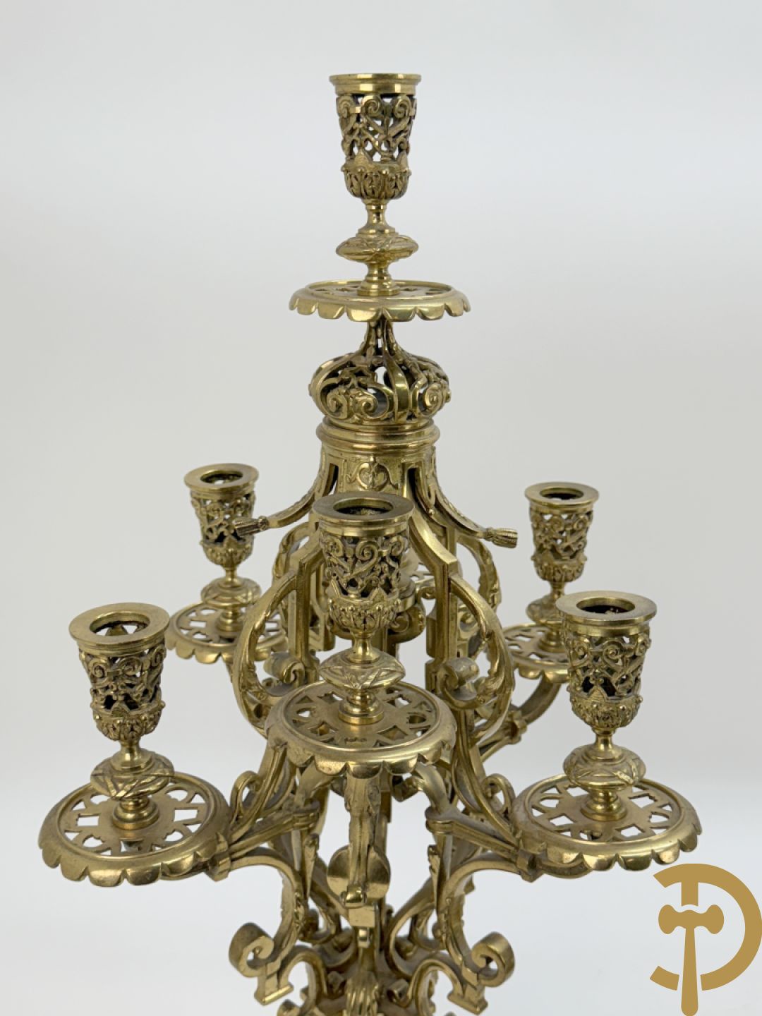 Driedelige bronzen vergulde garntiuur bestaande uit klok met medusahoofden en sfinxen, geflankeerd door paar zevenarmige kandelaars met accanthusranken en sfinxen
