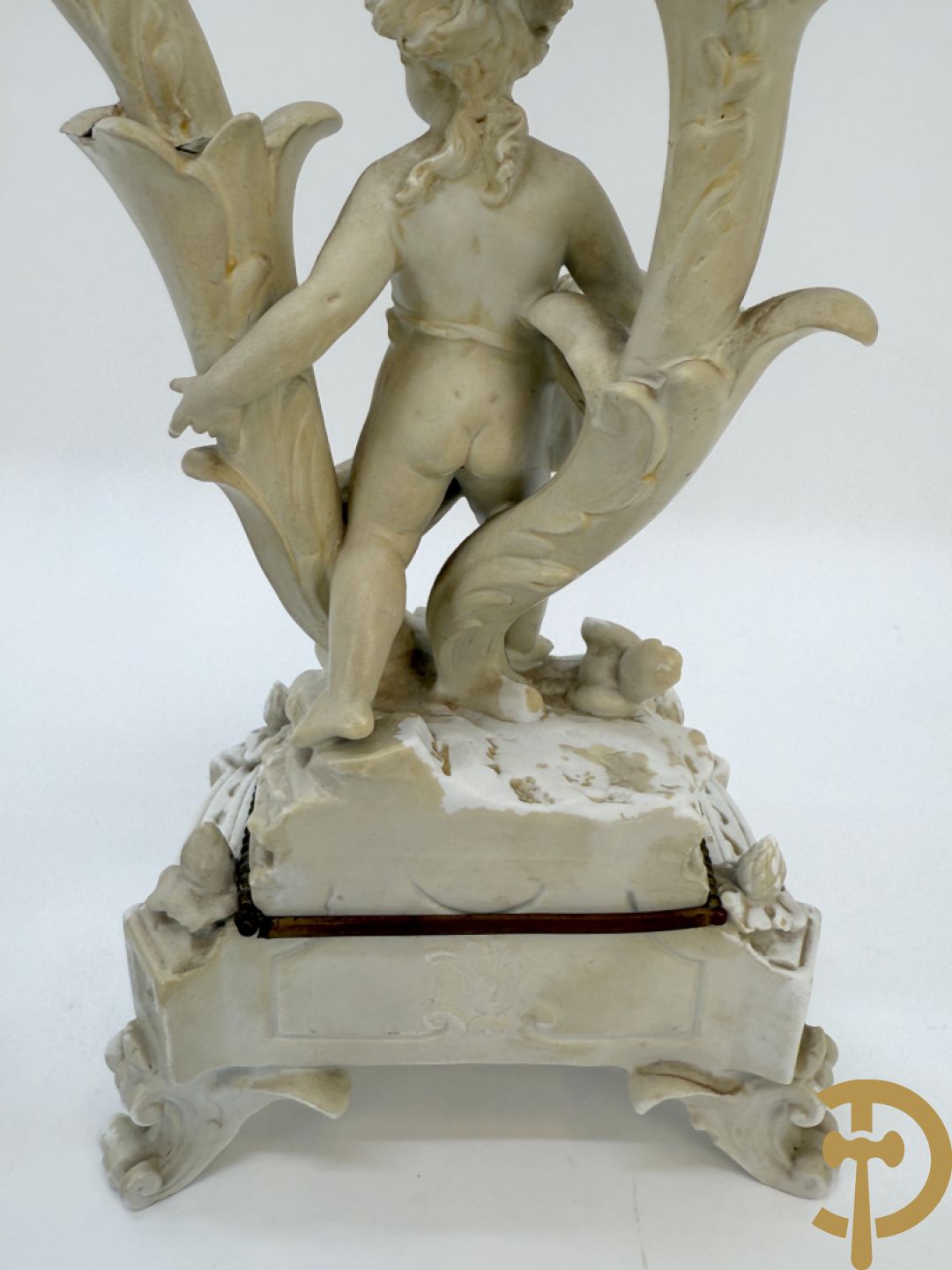 Driedelige porseleinen garnituur bestaande uit pendule bezet met lieftallig koppel, geflankeerd door paar kandelaars met cupido