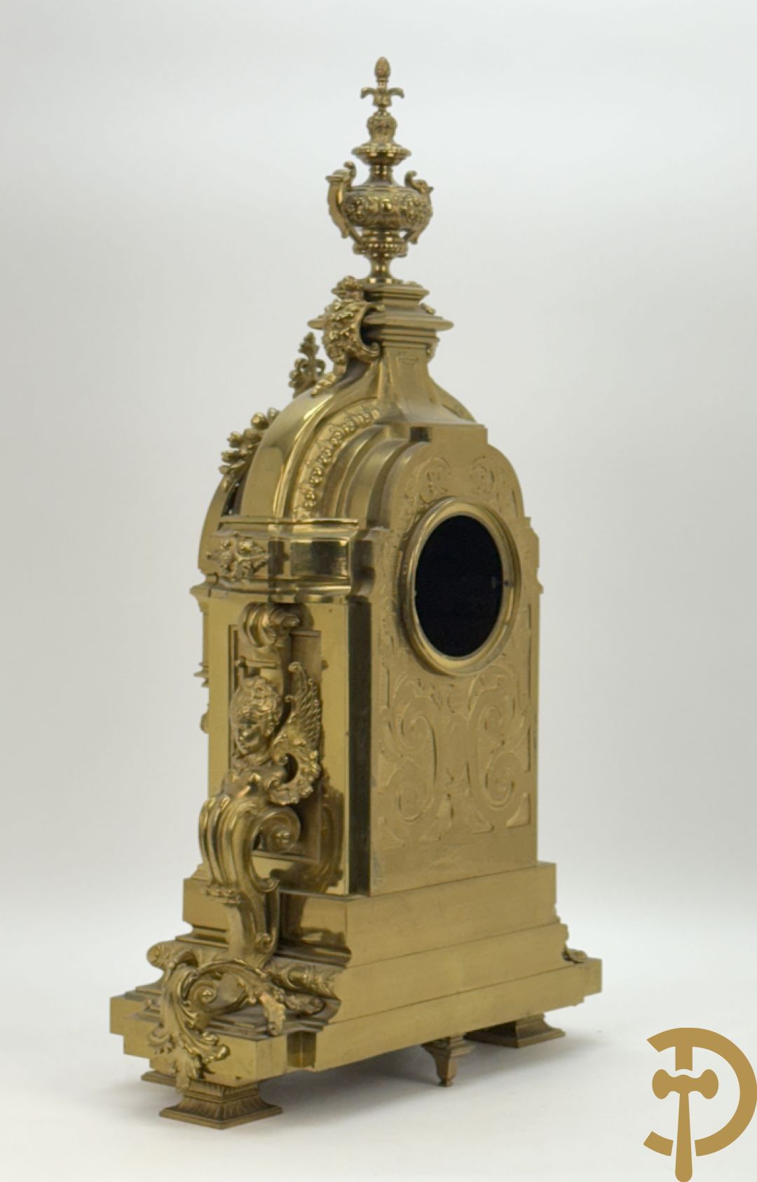Vuurvergulde bronzen pendule, zijdelings bezet met gevleugelde dames, bovenaan met amfoor