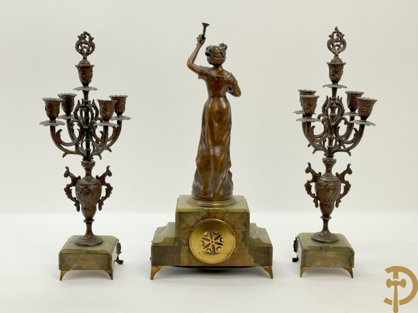 Driedelige zamak garnituur met dame Pavot met bloemen op uurwerk, Rucho getekend, geflankeerd door paar kandelaars