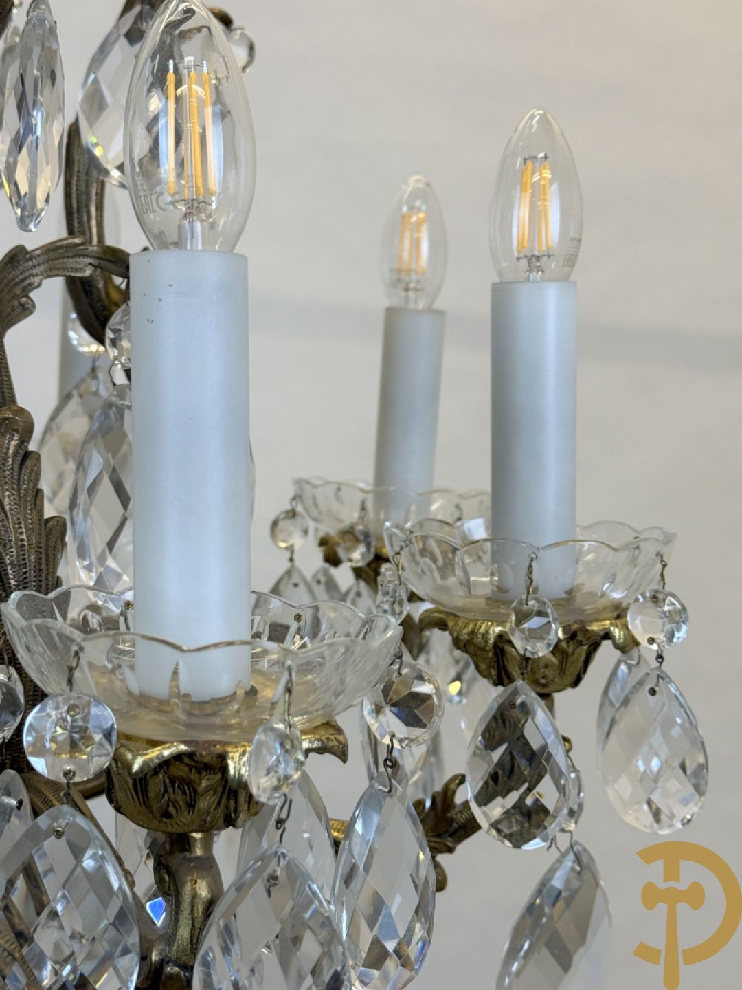 Achtarmige koperen luchter met kristallen bellen en binnenin met pinakel bezet